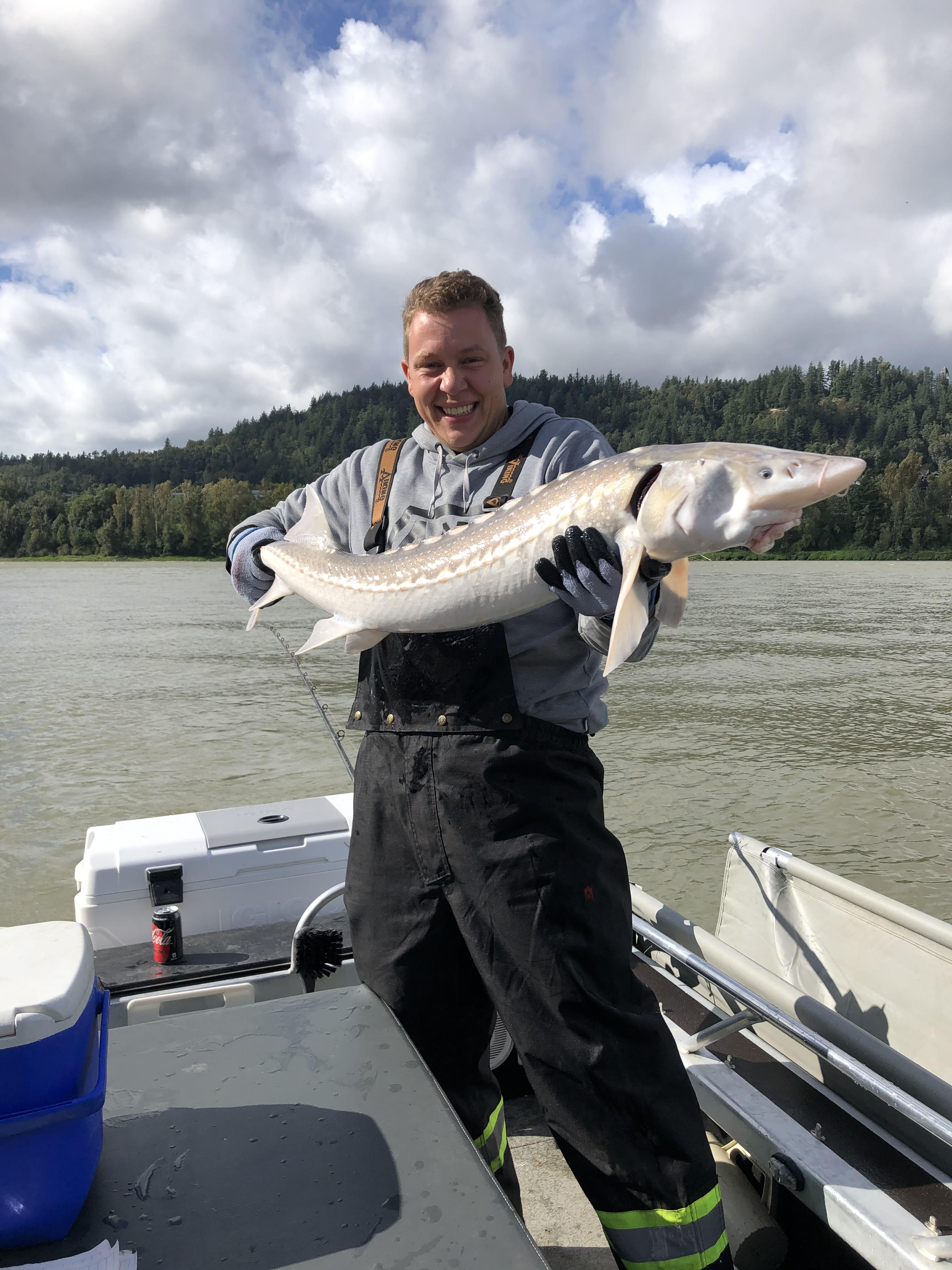 a man holding a 4 feet sturgeon on a boat