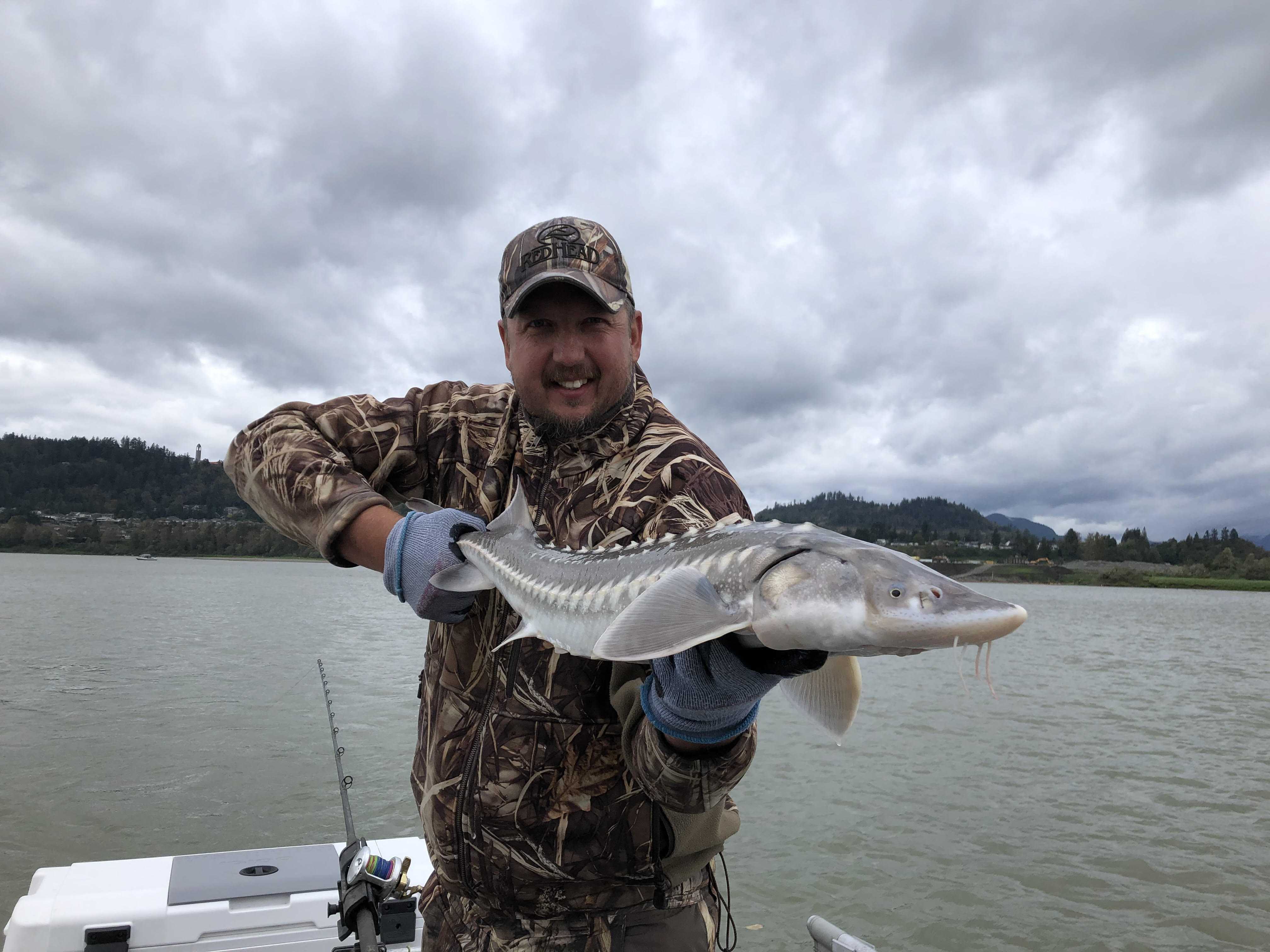 a man holding a juvenile sturgeon on a boat