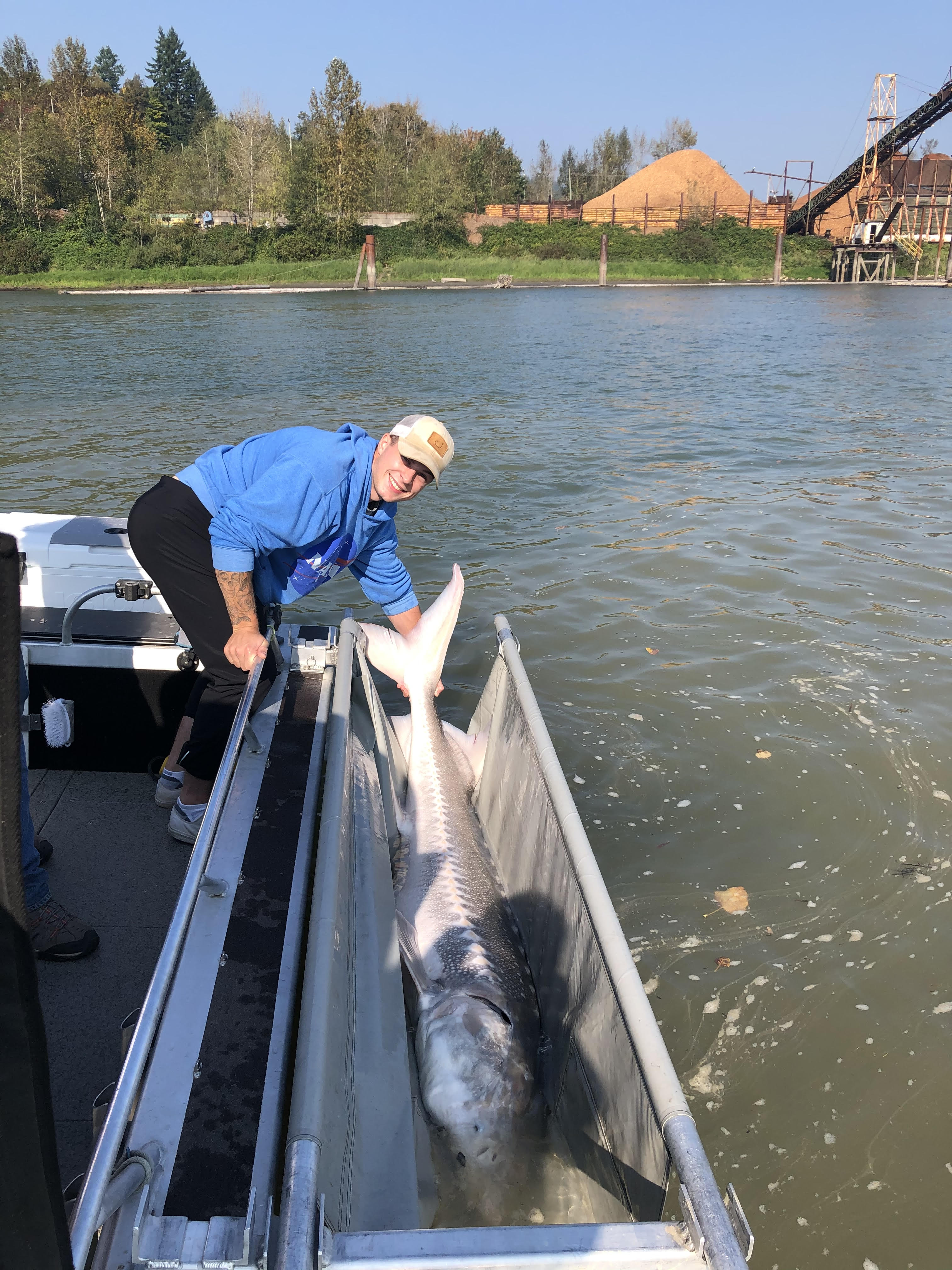 a man on a boat next to a giant sturgeon